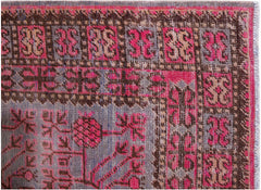 An antique handwoven Khotan rug featuring a pomegranate pattern in vibrant pink and brown tones.