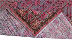 An antique handwoven Khotan rug featuring a vibrant pink pomegranate pattern on a grey background.
