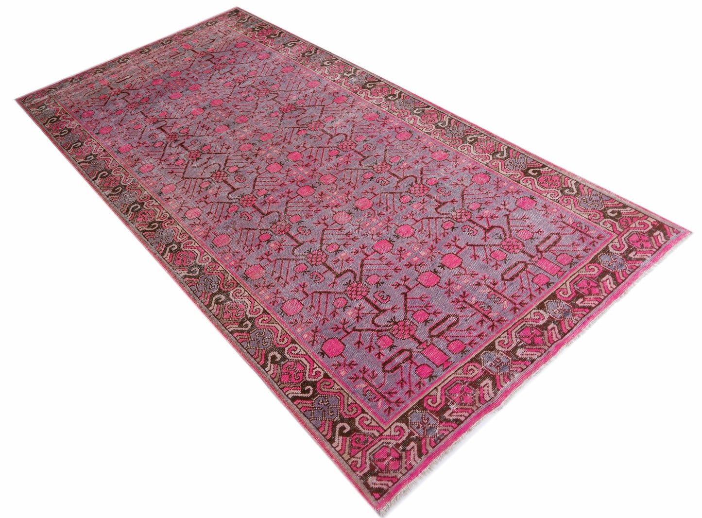 An antique handwoven Khotan rug featuring an intricate pomegranate pattern in vibrant pink tones.