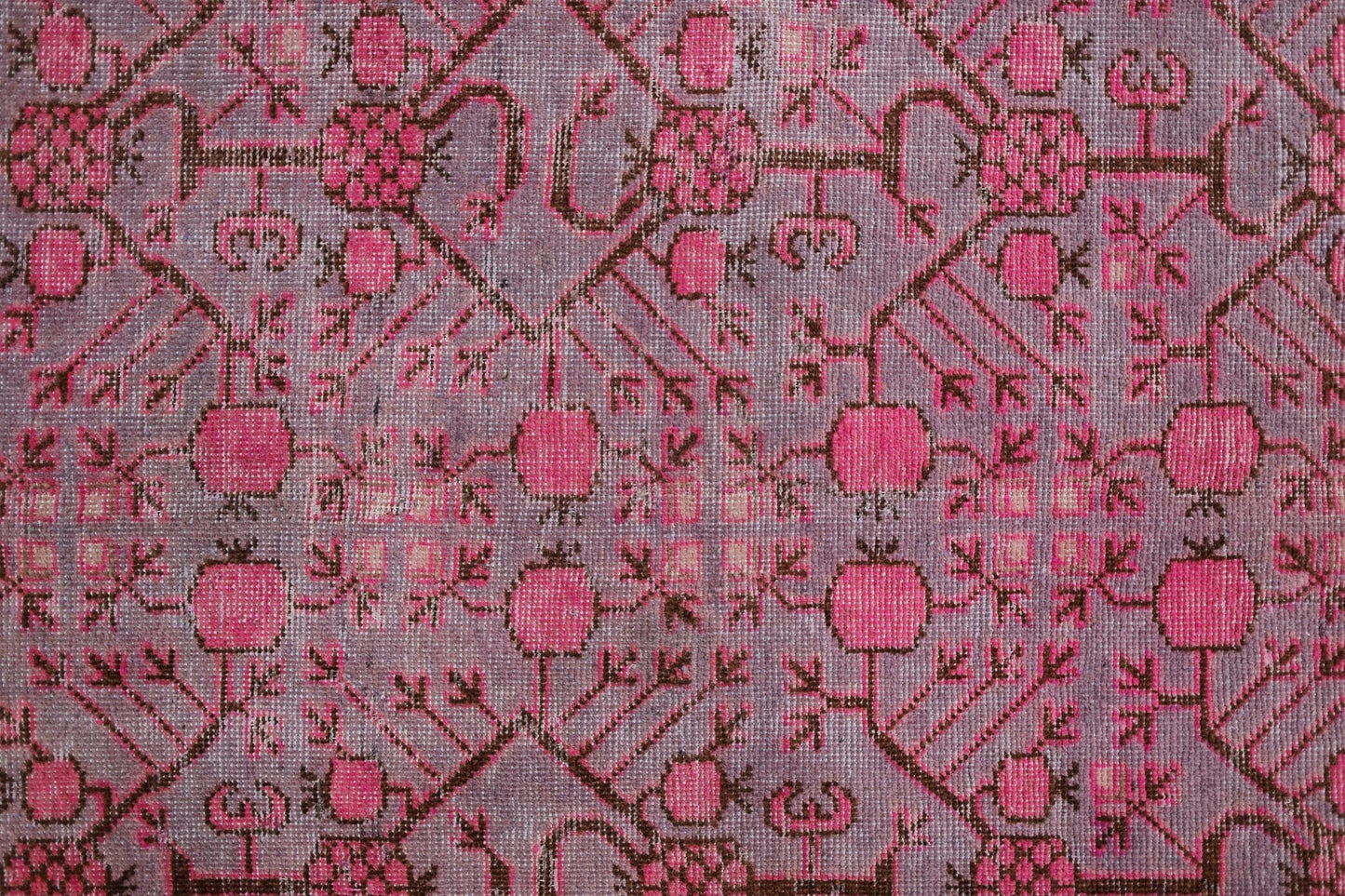 An antique handwoven Khotan rug featuring an intricate pomegranate pattern in vibrant pink.