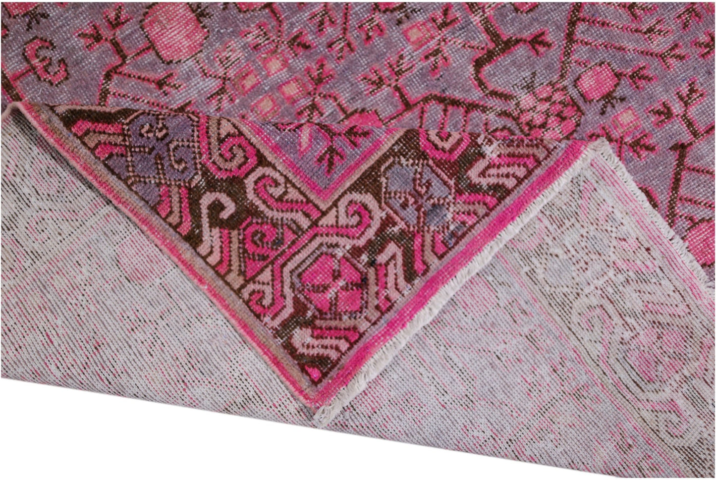An antique handwoven Khotan rug featuring a vibrant pink pomegranate pattern on a wool base.