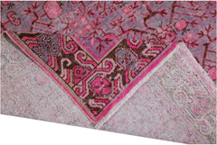 An antique handwoven Khotan rug featuring a vibrant pink pomegranate pattern on a wool base.