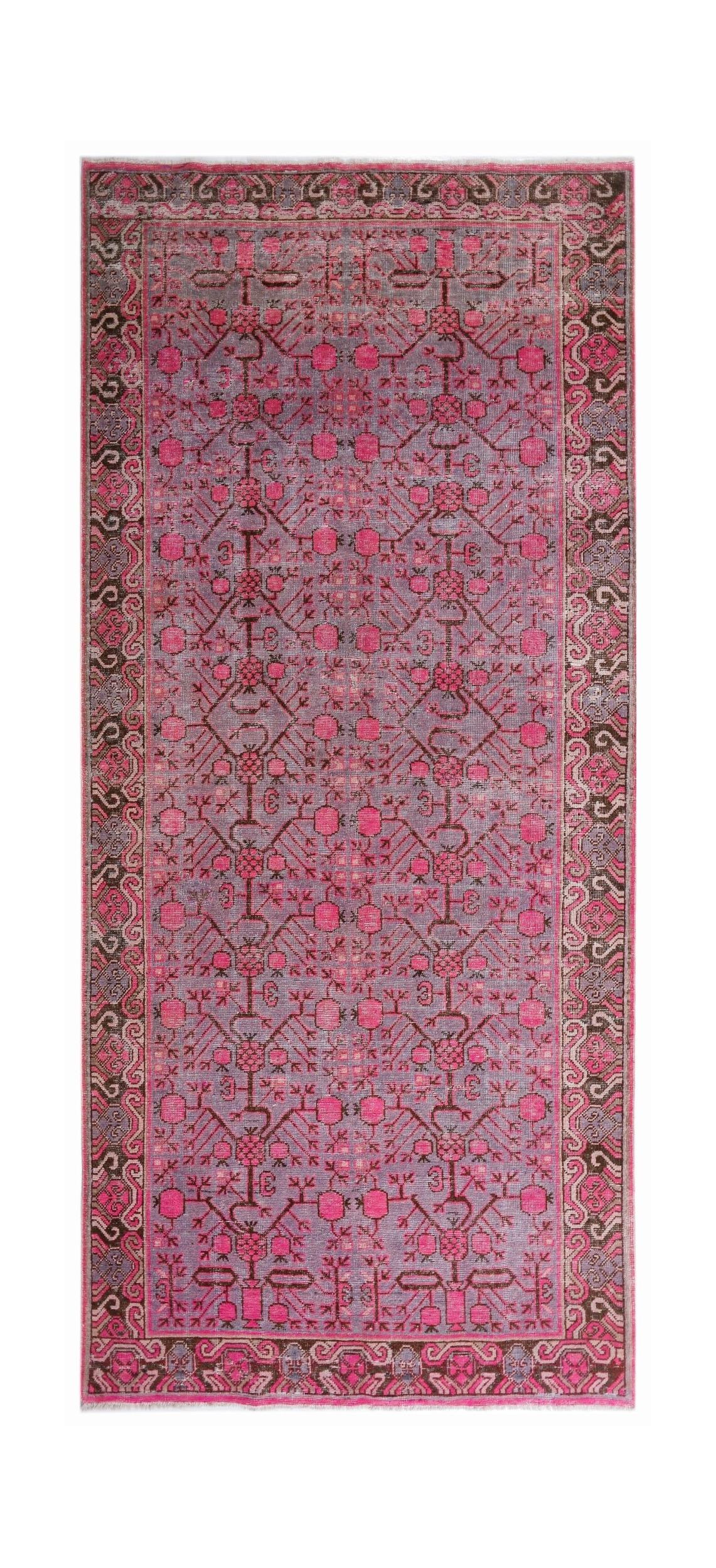 An antique handwoven Khotan rug featuring an intricate pomegranate pattern in vibrant pink tones.