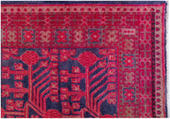 An antique handwoven Khotan rug featuring a vibrant pink pomegranate pattern on a dark blue field.