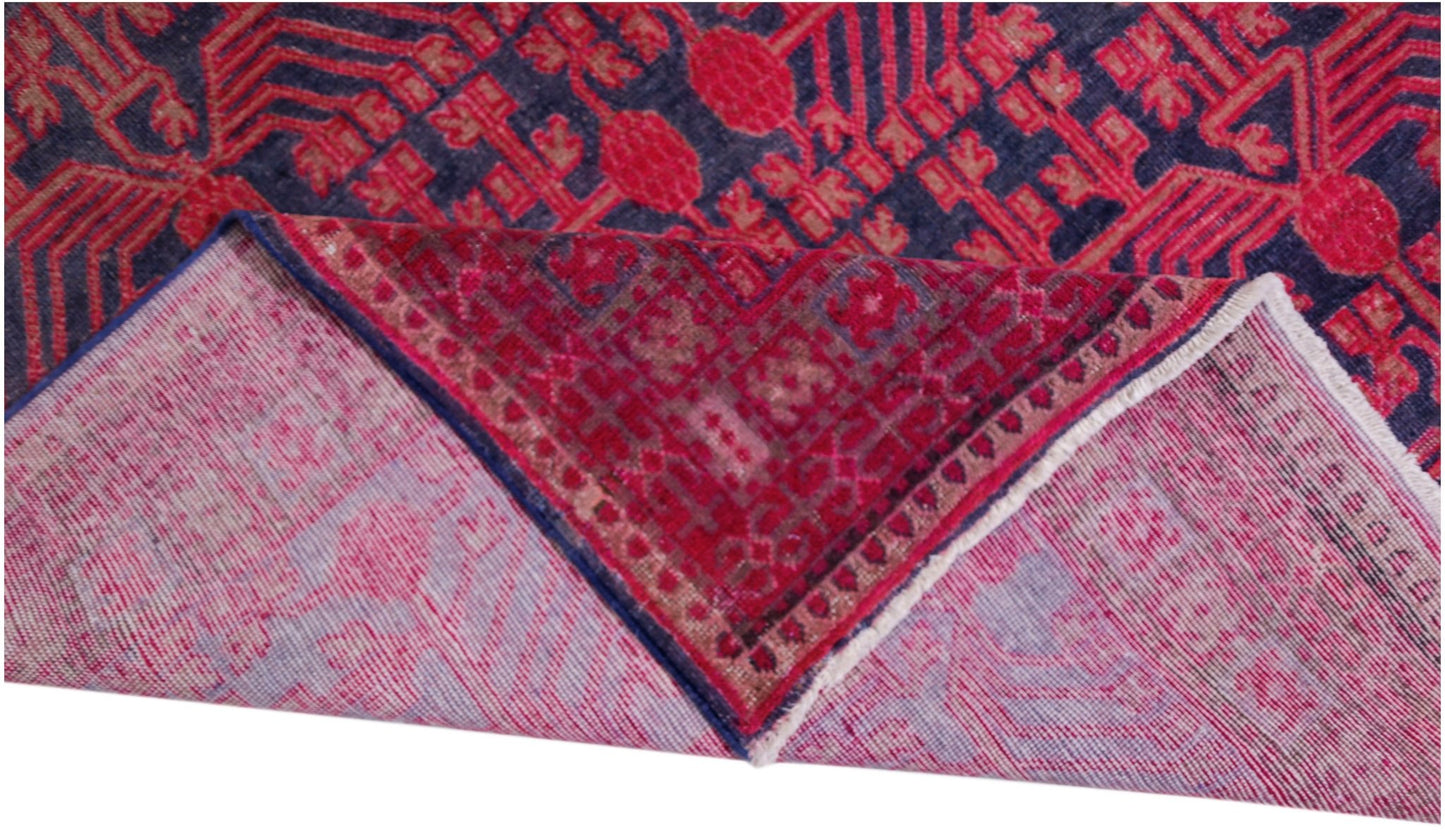 An antique handwoven Khotan rug featuring an intricate pomegranate pattern in vibrant pink tones.