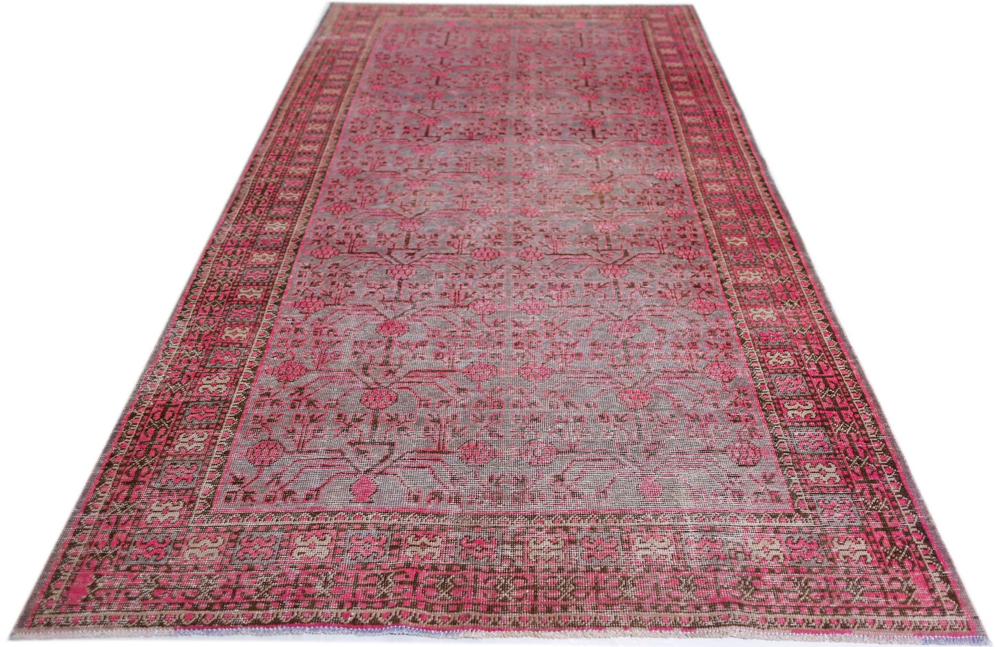 An antique handwoven Khotan rug featuring an intricate pomegranate pattern in vibrant pink.