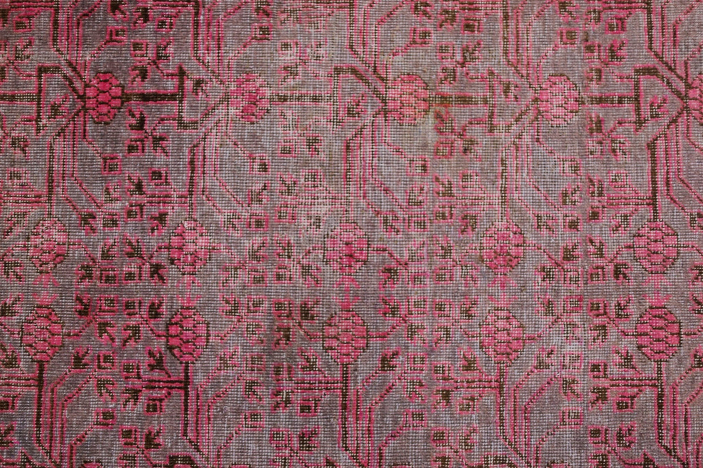 An antique handwoven Khotan rug featuring an intricate pomegranate pattern in vibrant pink.