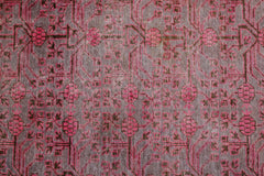 An antique handwoven Khotan rug featuring an intricate pomegranate pattern in vibrant pink.