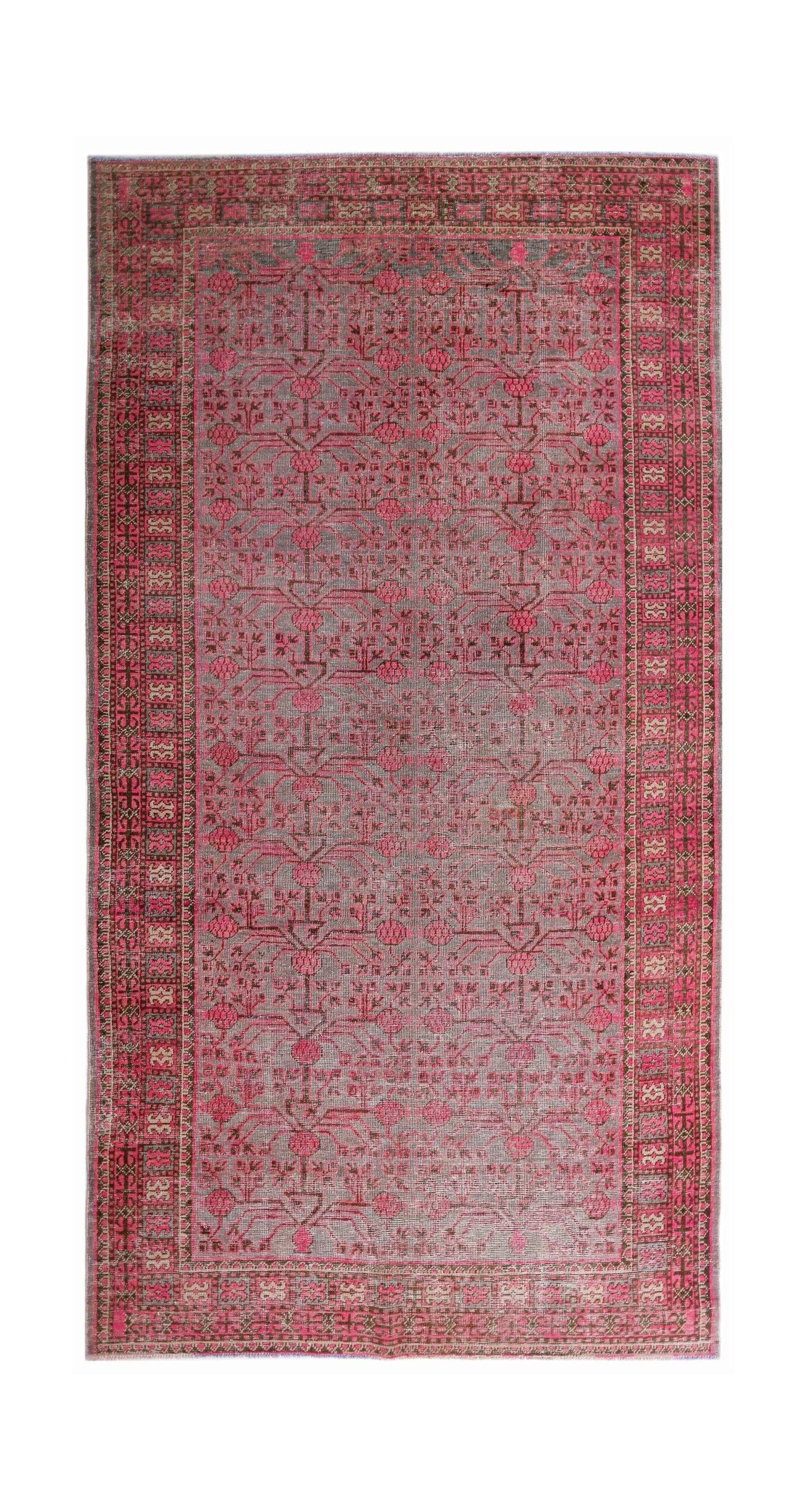 An antique handwoven Khotan rug featuring a vibrant pink pomegranate pattern on a grey field.