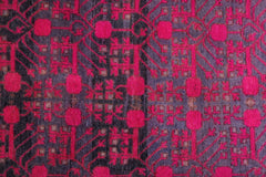 An antique handwoven Khotan rug featuring an intricate pomegranate pattern in vibrant pink.