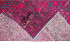 An antique handwoven Khotan rug featuring an intricate pomegranate pattern in vibrant pink.