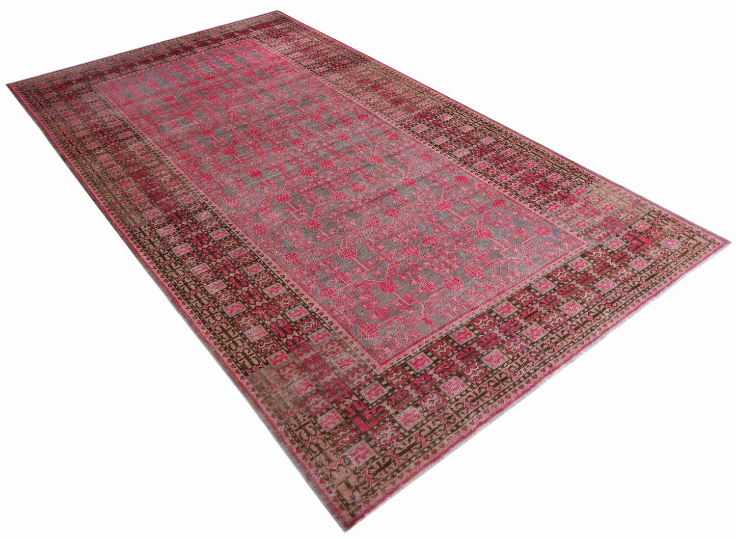 An antique handwoven Khotan rug featuring a vibrant pink pomegranate pattern on a grey field.