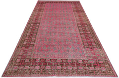 An antique handwoven Khotan rug featuring a vibrant pink pomegranate pattern on a grey field.