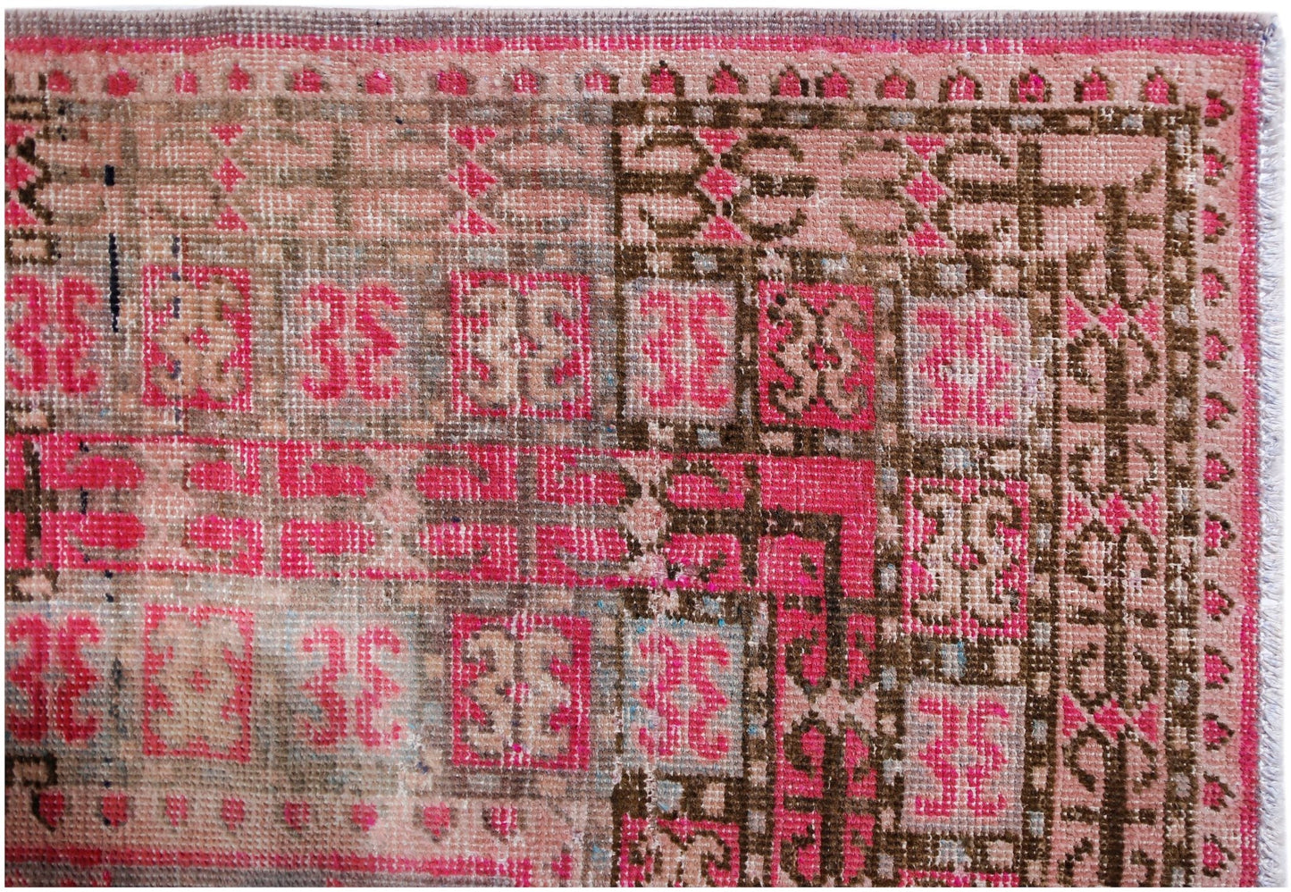 An antique handwoven Khotan rug featuring a geometric pomegranate pattern in vibrant pink and brown.