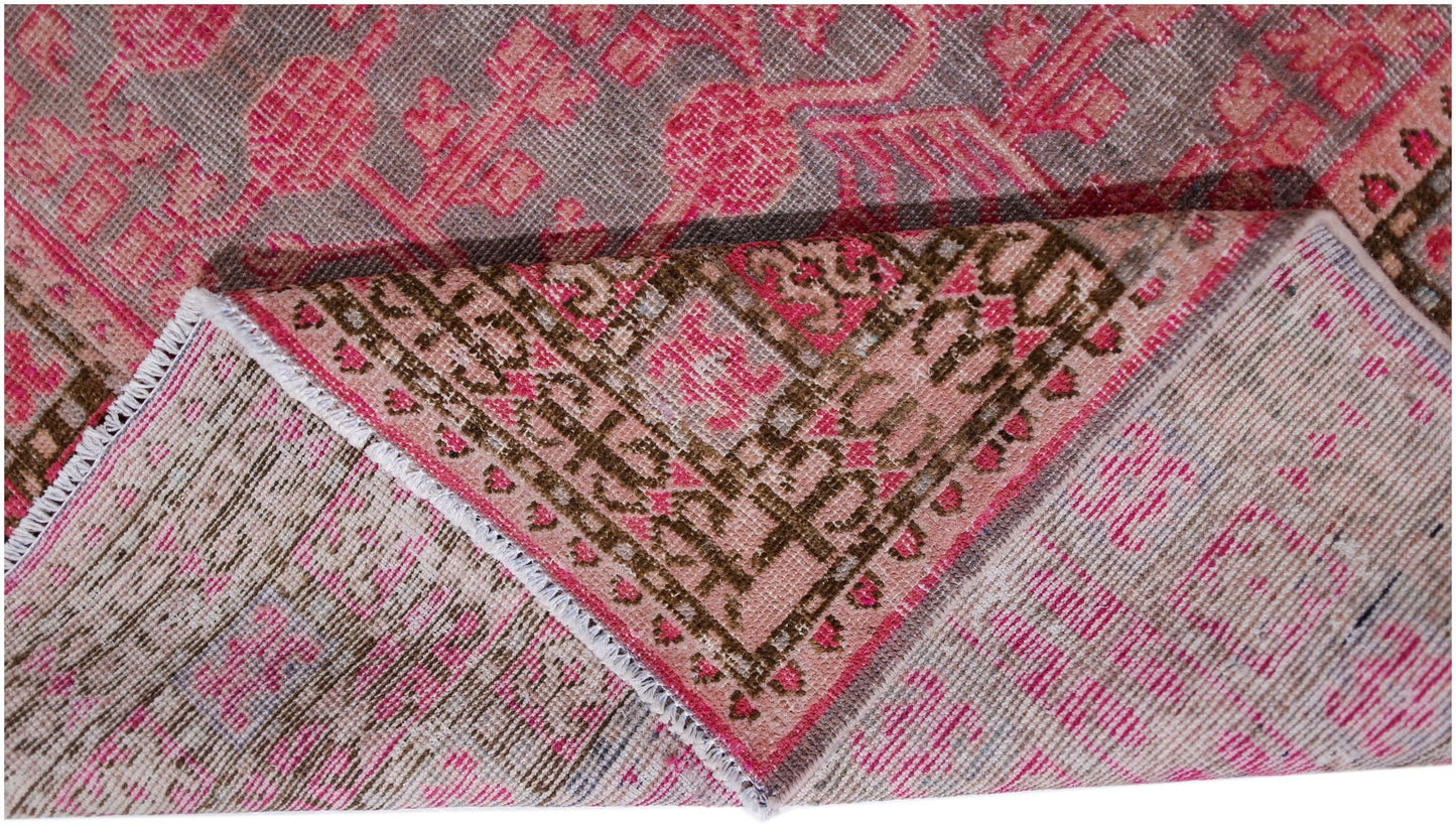 An antique handwoven Khotan rug featuring an intricate pomegranate pattern in vibrant pink tones.