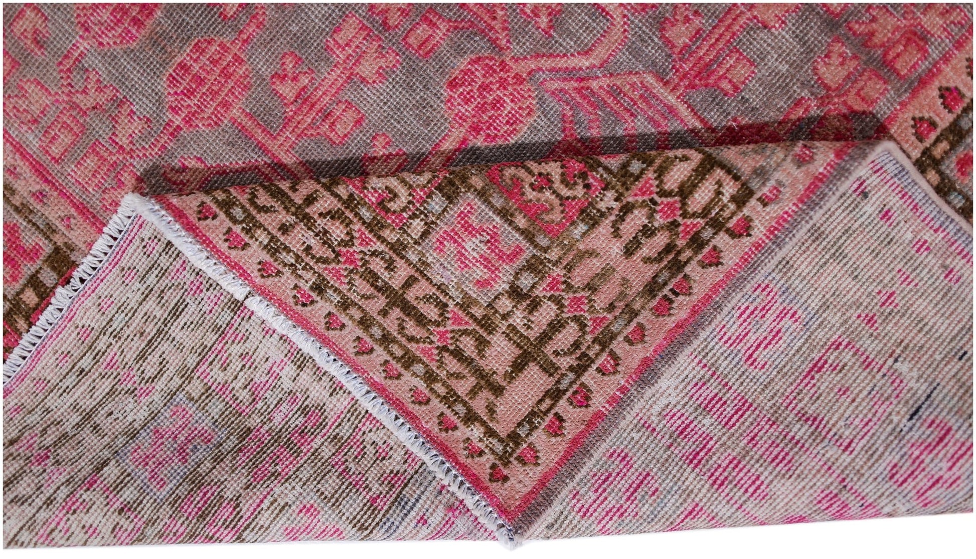 An antique handwoven Khotan rug featuring an intricate pomegranate pattern in vibrant pink tones.