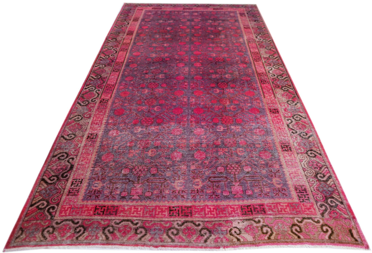 An antique handwoven Khotan rug featuring a vibrant pink pomegranate pattern on a wool base.