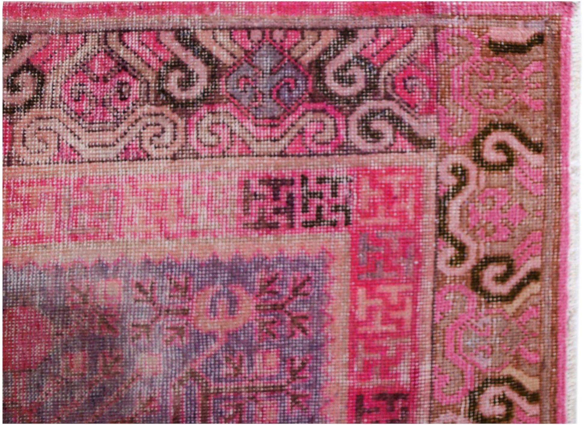 A close-up of an antique handwoven Khotan rug featuring a vibrant pink pomegranate pattern.