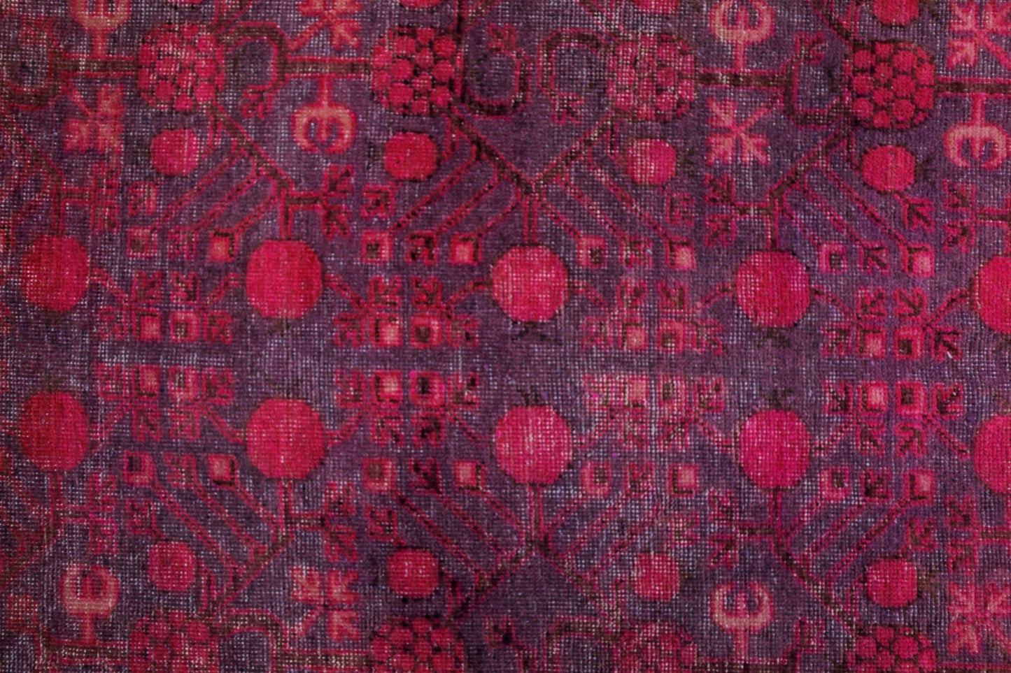 An antique handwoven Khotan rug featuring an intricate pomegranate pattern in vibrant pink tones.