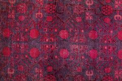 An antique handwoven Khotan rug featuring an intricate pomegranate pattern in vibrant pink tones.