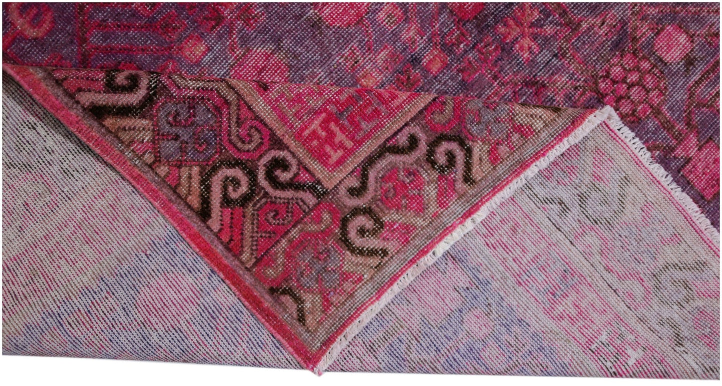 An antique handwoven Khotan rug featuring an intricate pomegranate pattern in vibrant pink.