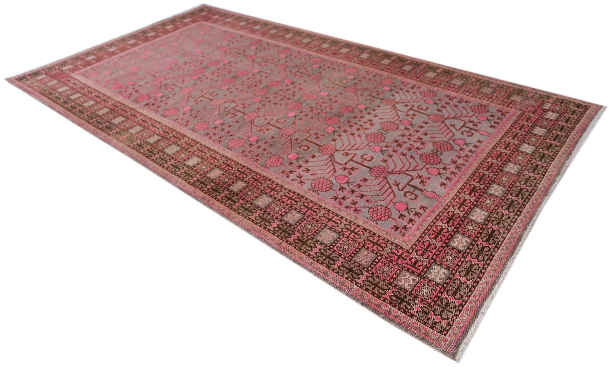 An antique handwoven Khotan rug featuring a pink pomegranate pattern on a grey wool field.