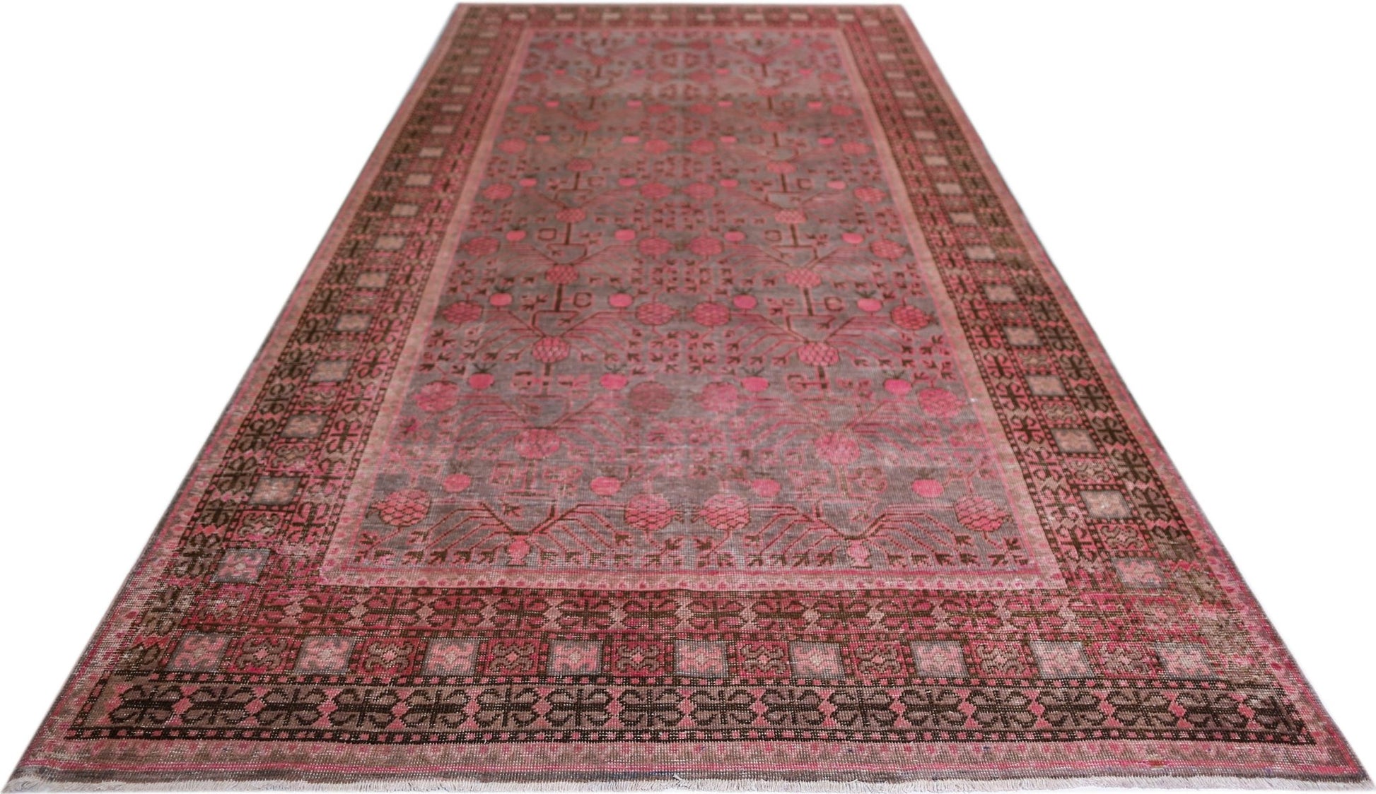 An antique handwoven Khotan rug featuring a pink pomegranate pattern on a muted background.