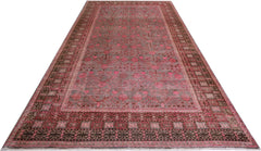 An antique handwoven Khotan rug featuring a pink pomegranate pattern on a muted background.