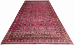 An antique handwoven Khotan rug featuring an intricate pink pomegranate pattern on a grey field.