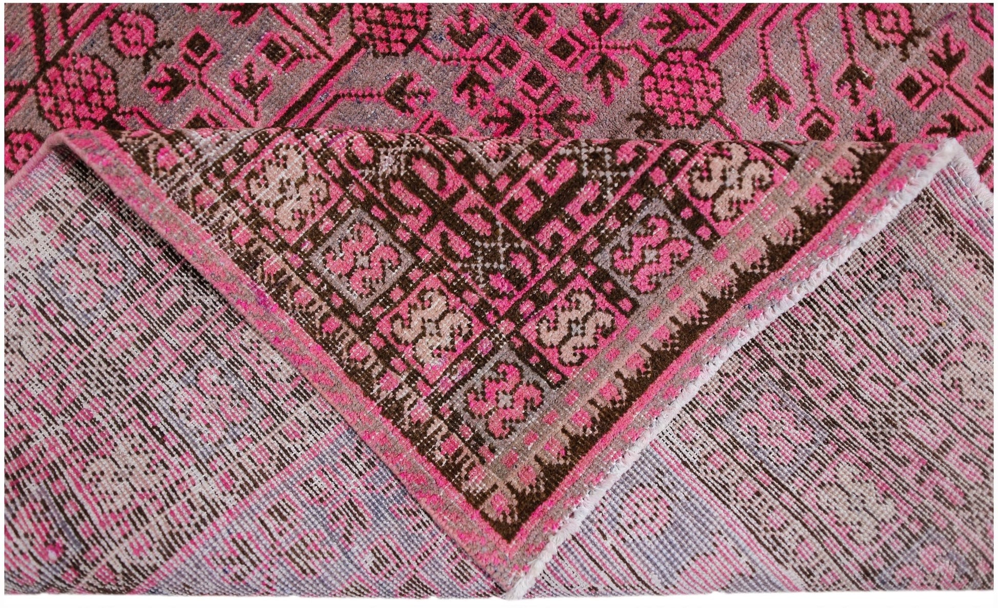 An antique handwoven Khotan rug featuring an intricate pomegranate pattern in vibrant pink.