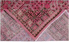 An antique handwoven Khotan rug featuring an intricate pomegranate pattern in vibrant pink.
