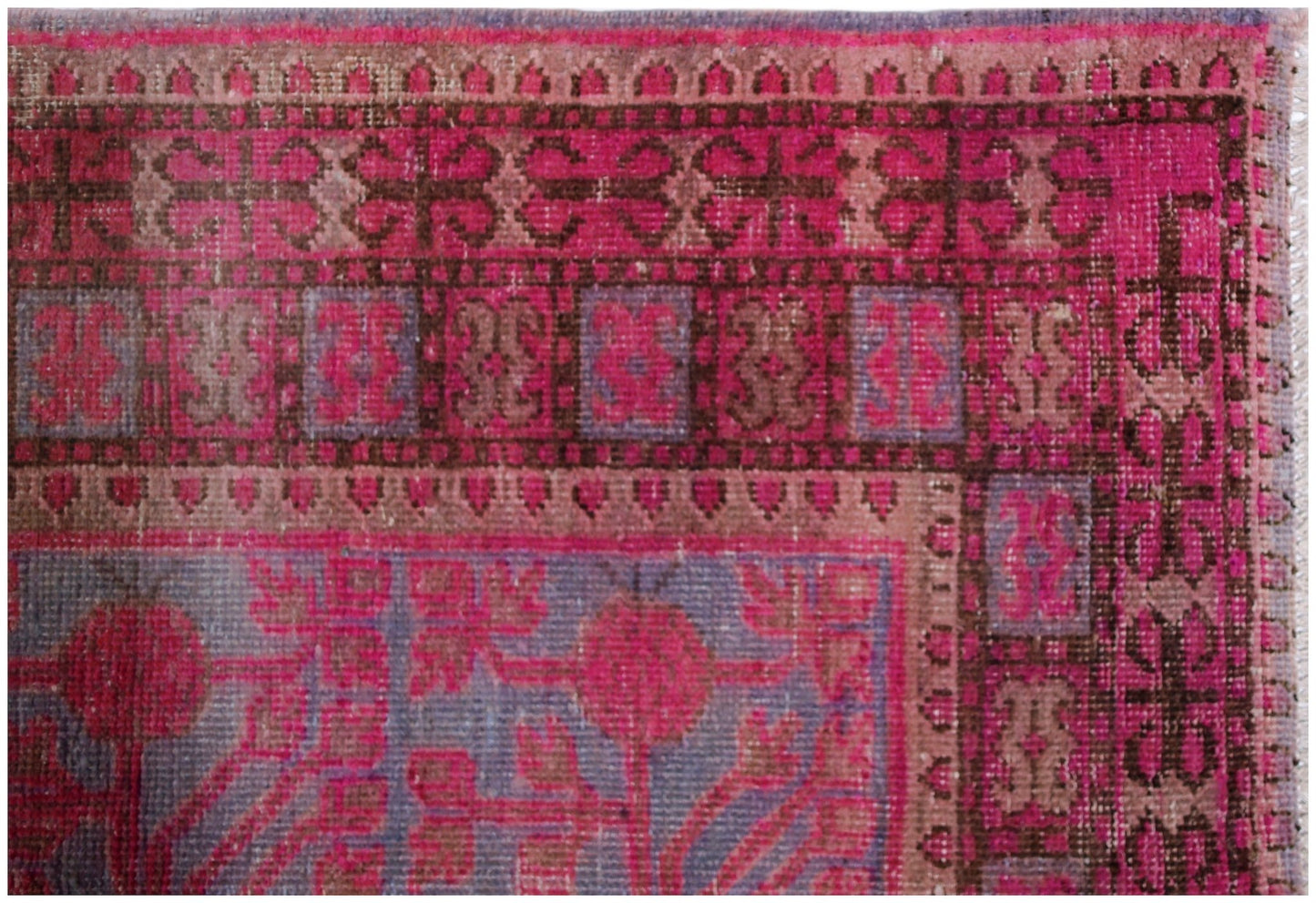 An antique handwoven Khotan rug featuring an intricate pomegranate pattern in vibrant pink and blue.