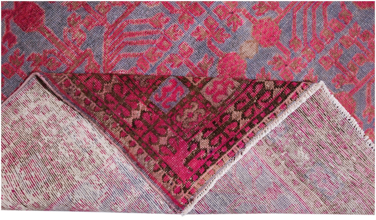 An antique handwoven Khotan rug featuring an intricate pink pomegranate pattern on a grey base.