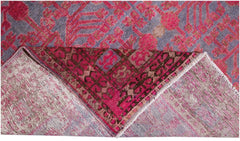 An antique handwoven Khotan rug featuring an intricate pink pomegranate pattern on a grey base.
