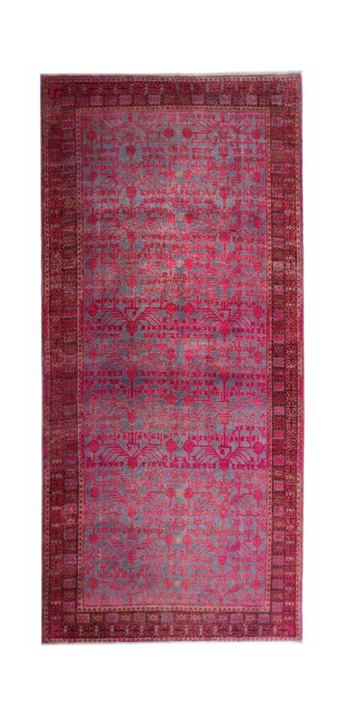 An antique handwoven Chinese Khotan rug featuring an intricate pomegranate pattern in vibrant pink.