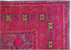An antique handwoven Khotan rug featuring a vibrant pink pomegranate pattern on a wool base.