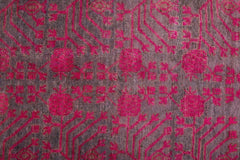 An antique handwoven Khotan rug featuring an intricate pomegranate pattern in vibrant pink.