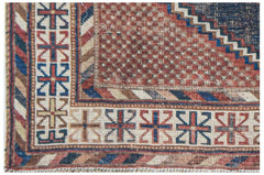 A corner view of an antique handwoven Persian rug featuring geometric patterns in red and blue.