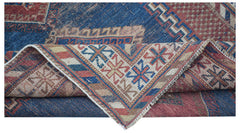 An antique Persian rug featuring a blue field with geometric patterns and a folded corner.