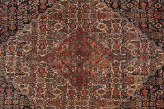 An antique Persian Senneh rug featuring a detailed geometric medallion in red, blue, and beige.