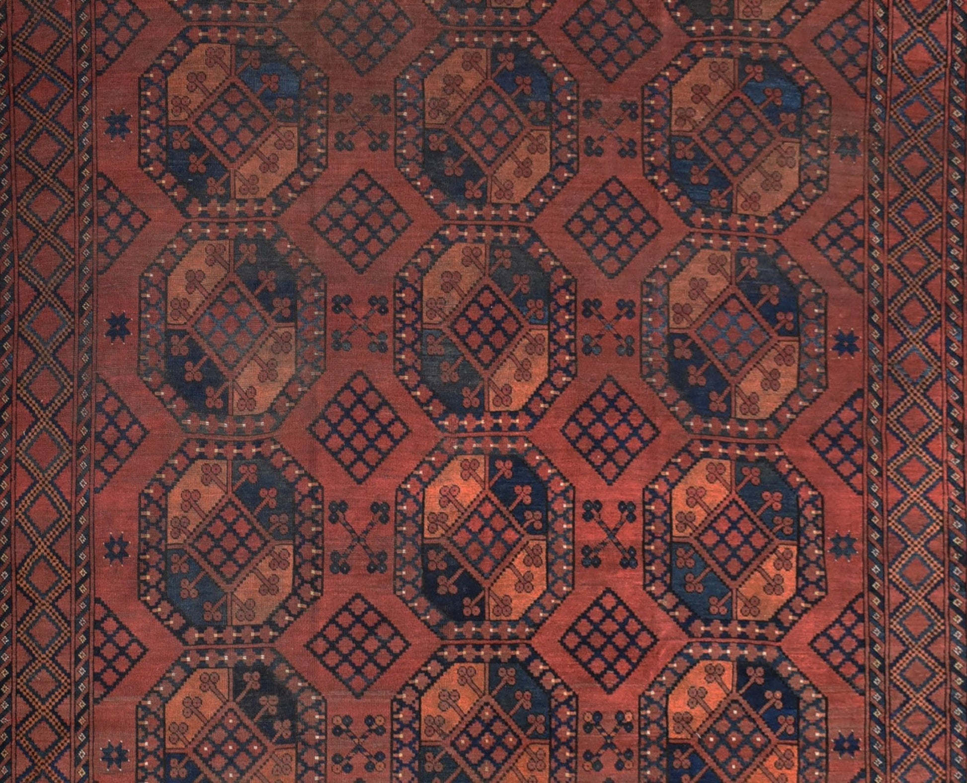 An antique Afghan Turkmen rug featuring a repeating geometric elephant foot motif in red and blue.