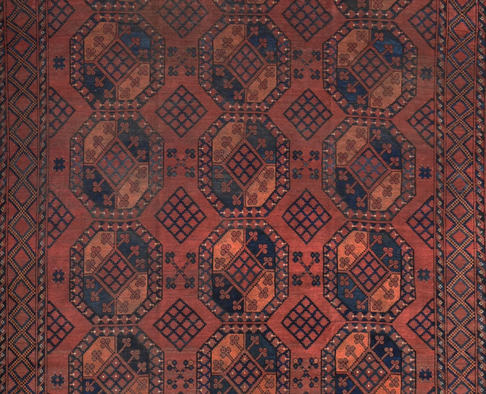 An antique Afghan Turkmen rug featuring a repeating geometric elephant foot motif in red and blue.