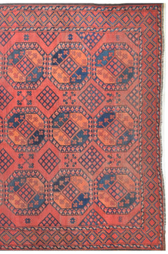 An antique Afghan Turkmen rug featuring a repeating geometric elephant foot motif in red and blue.