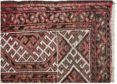 A close-up of an antique Afghan Turkmen rug featuring geometric elephant foot motifs in red and brown.