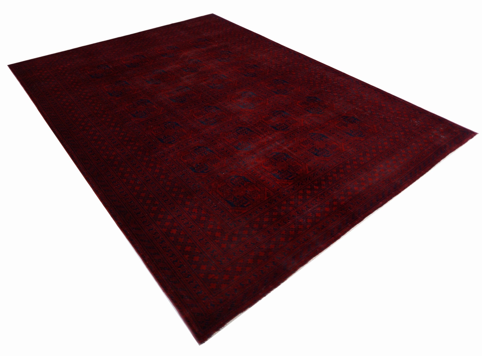 An antique Afghan Turkmen rug featuring a deep red field with repeating elephant foot motifs.