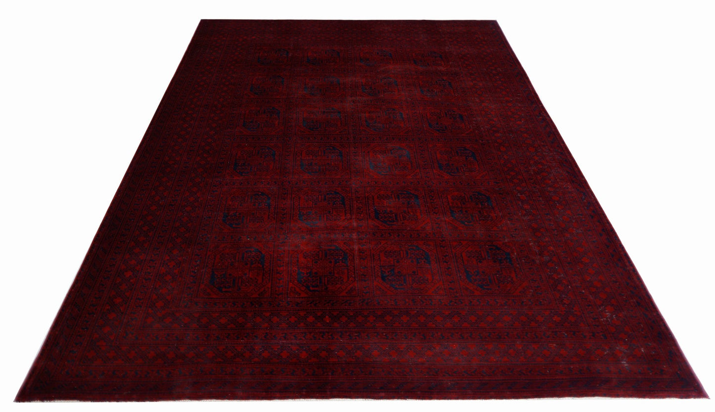 An antique Afghan Turkmen rug featuring a deep red field with repeating blue elephant foot motifs.