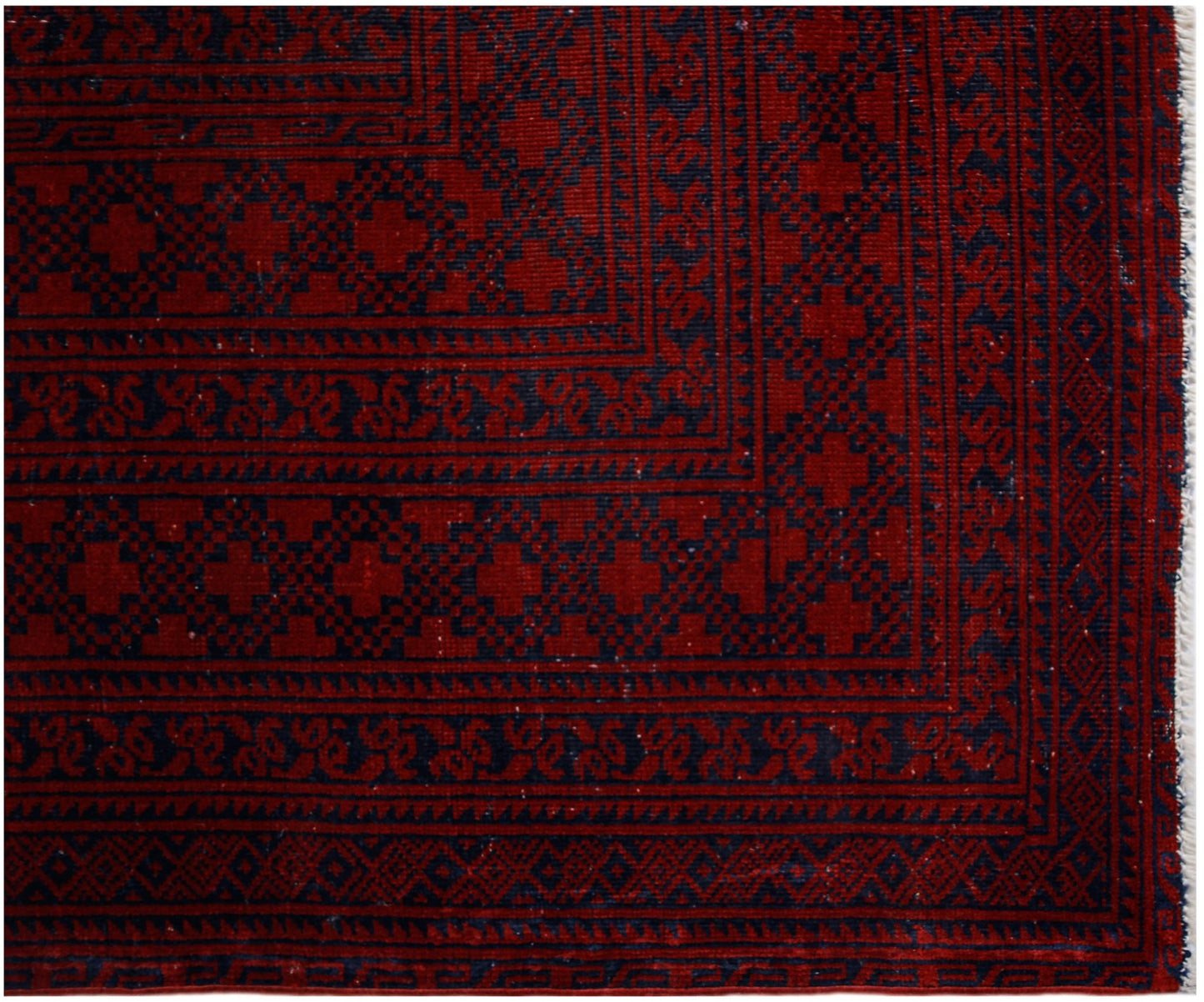 An antique Afghan Turkmen rug featuring traditional red and navy geometric elephant foot motifs.