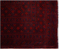 An antique Afghan Turkmen rug featuring traditional red and navy geometric elephant foot motifs.