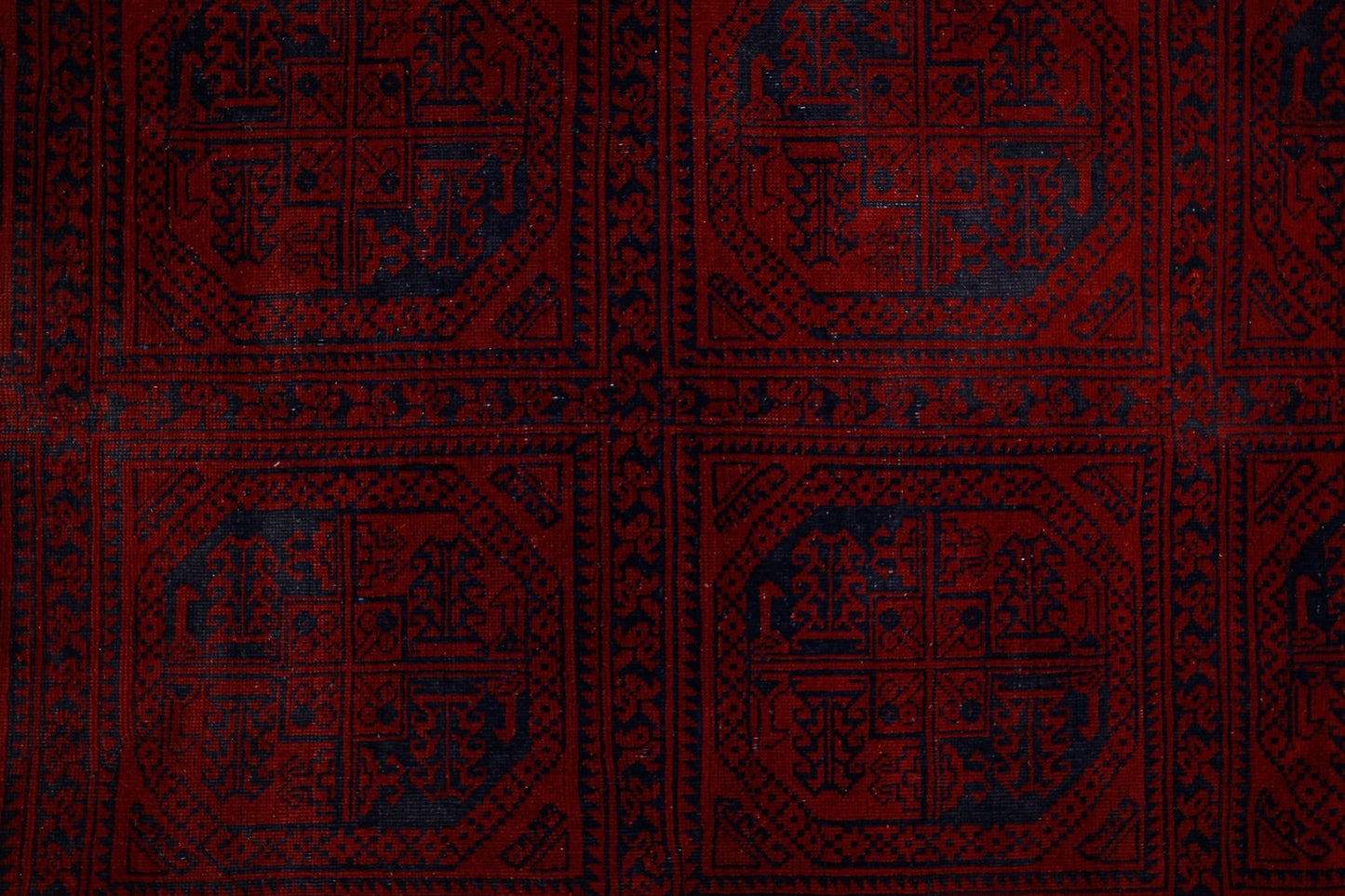An antique Afghan Turkmen rug featuring a repeating pattern of dark blue elephant foot motifs on a deep red background.