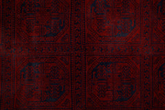 An antique Afghan Turkmen rug featuring a repeating pattern of dark blue elephant foot motifs on a deep red background.